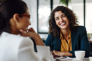 Women smile and chat over coffee as they discuss the benefits of a residential treatment program