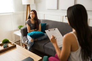 Teen sits on couch and talks to therapist during borderline personality disorder treatment