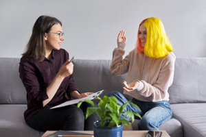 Teen engages with therapist while sitting on couch during a person-centered therapy session