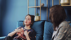 Teen leans back on couch and chats with therapist as she begins psychosis treatment